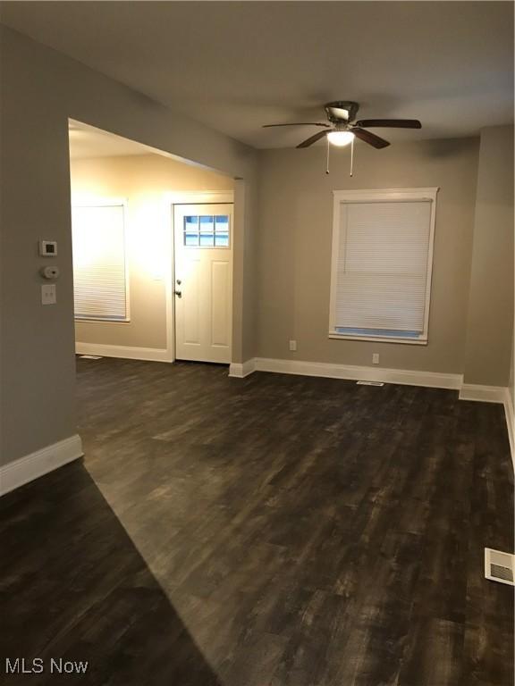 interior space featuring visible vents, dark wood finished floors, baseboards, and ceiling fan