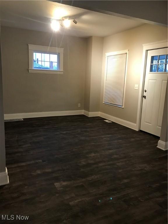 spare room featuring dark wood-style floors and baseboards