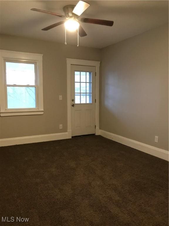 entryway featuring dark colored carpet, a healthy amount of sunlight, and baseboards