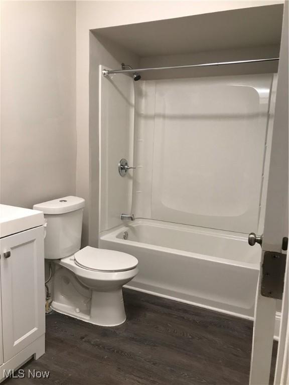 bathroom featuring toilet, shower / tub combination, wood finished floors, and vanity