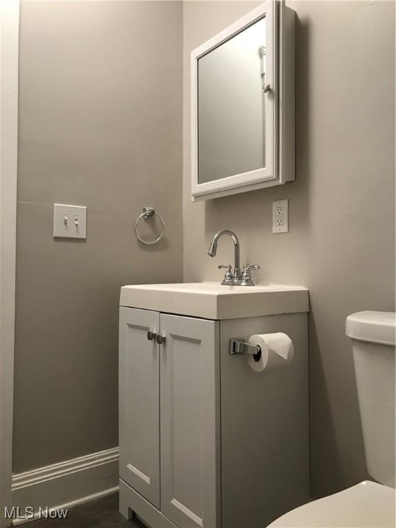 bathroom featuring baseboards, vanity, and toilet