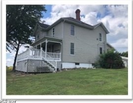 rear view of property with a yard and stairway