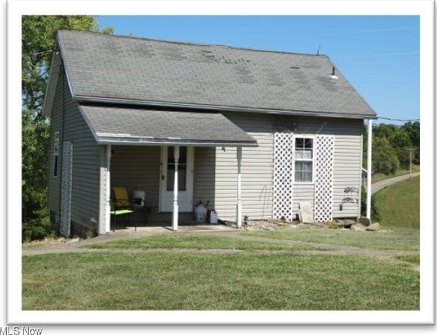 back of property with a yard and roof with shingles