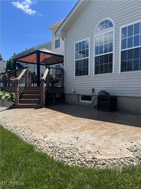 view of side of property with a patio area, a deck, and a gazebo