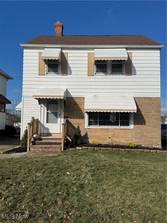 view of front of property with a chimney and a front lawn