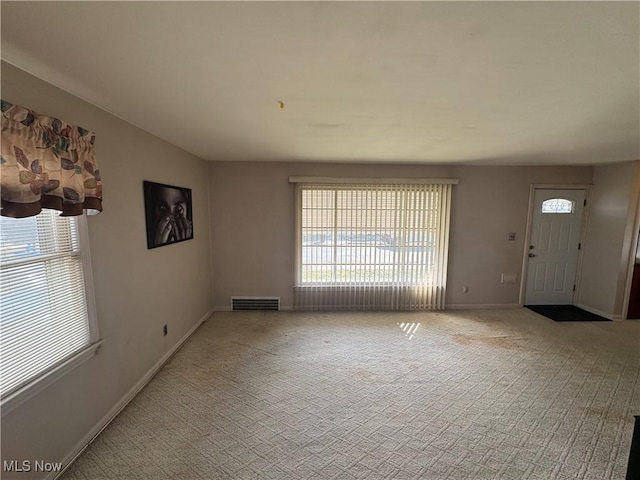 interior space with a healthy amount of sunlight, carpet, baseboards, and visible vents