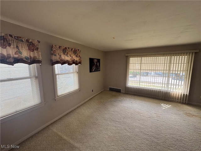 empty room featuring carpet, visible vents, and baseboards