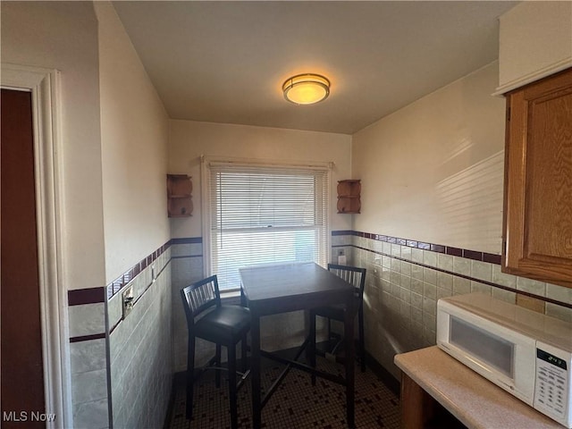 dining room featuring a wainscoted wall and tile walls