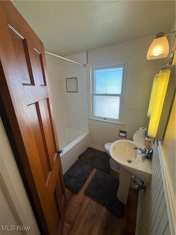 bathroom featuring toilet, wood finished floors, and shower / bathtub combination