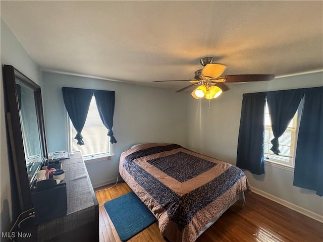 bedroom featuring ceiling fan, baseboards, and wood finished floors