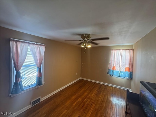 unfurnished room featuring visible vents, ceiling fan, baseboards, and hardwood / wood-style flooring