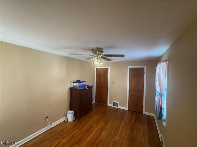 unfurnished bedroom with ceiling fan, dark wood-type flooring, visible vents, and baseboards