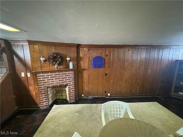 interior space featuring a brick fireplace, wooden walls, and a textured ceiling