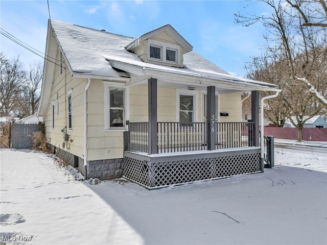 bungalow-style house with covered porch and fence