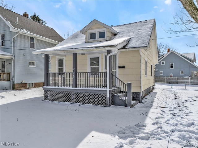 bungalow-style house featuring covered porch and fence