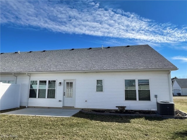 rear view of house with a patio area, central AC, a lawn, and roof with shingles