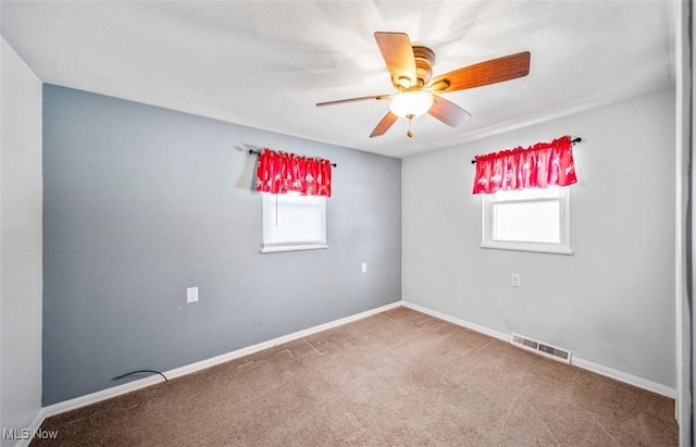 empty room featuring a ceiling fan, baseboards, visible vents, and carpet flooring