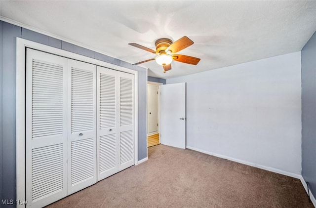 unfurnished bedroom with ceiling fan, a closet, carpet, and baseboards