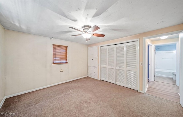 unfurnished bedroom featuring carpet floors, ceiling fan, baseboards, and a closet