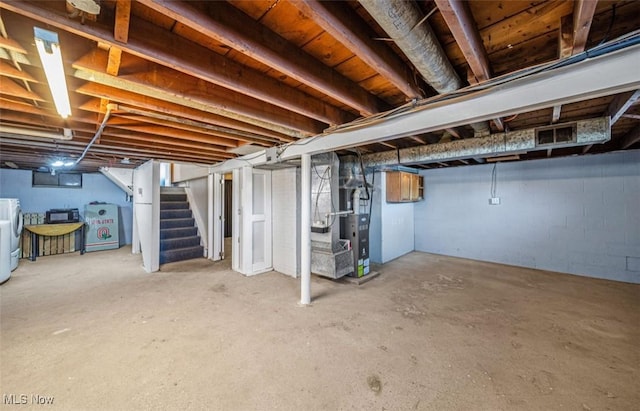 unfinished basement featuring heating unit, stairs, and washer and clothes dryer