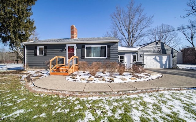 view of front of home with an attached garage, a chimney, and aphalt driveway