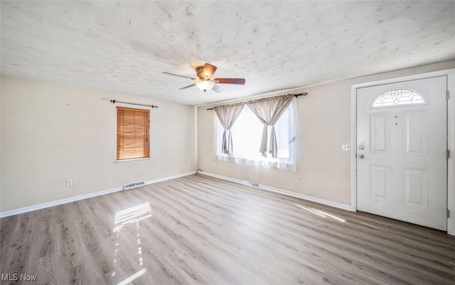 entryway with visible vents, a textured ceiling, baseboards, and wood finished floors