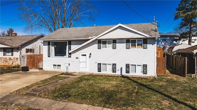 view of front of house featuring a patio area, roof with shingles, fence, and a front yard