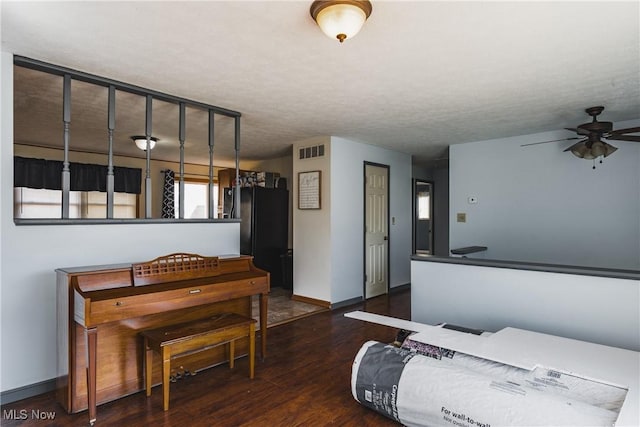 interior space with a textured ceiling, wood finished floors, visible vents, and baseboards