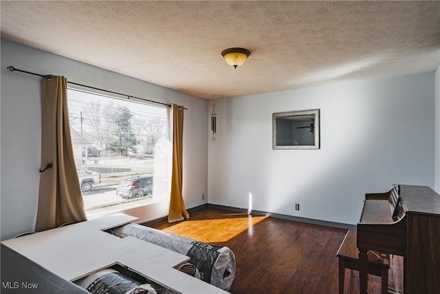 bedroom featuring a textured ceiling, wood finished floors, and baseboards