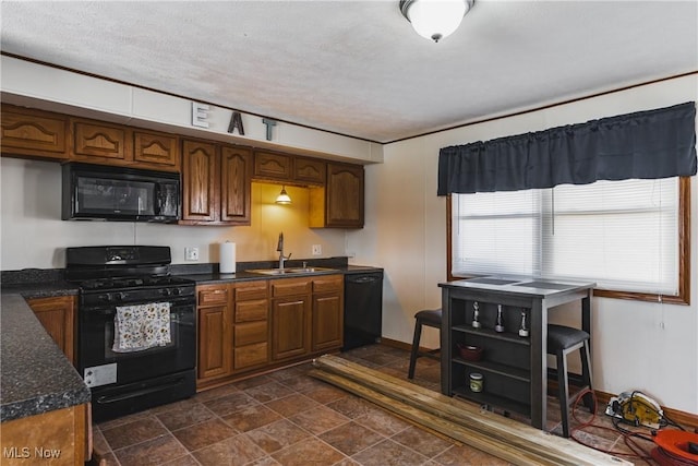 kitchen with dark countertops, brown cabinets, a textured ceiling, black appliances, and a sink