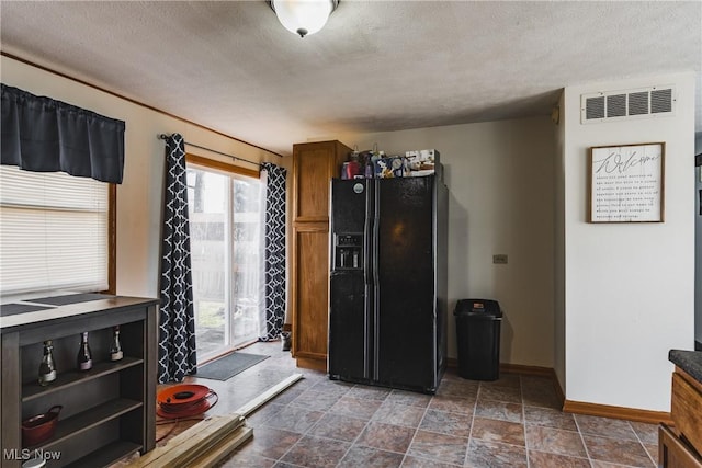 kitchen featuring dark countertops, visible vents, black fridge with ice dispenser, a textured ceiling, and baseboards