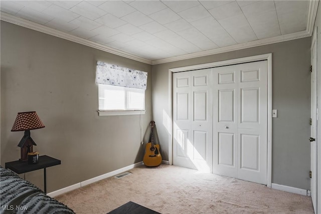 carpeted bedroom with ornamental molding, a closet, visible vents, and baseboards