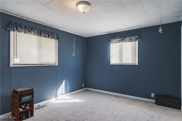 carpeted empty room featuring baseboards and visible vents