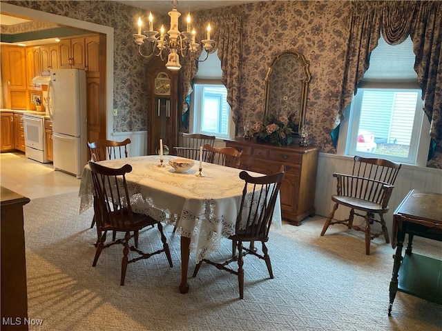 dining room with a wainscoted wall, a chandelier, and wallpapered walls