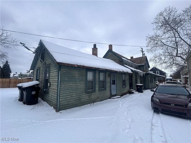 snow covered property with fence and a chimney