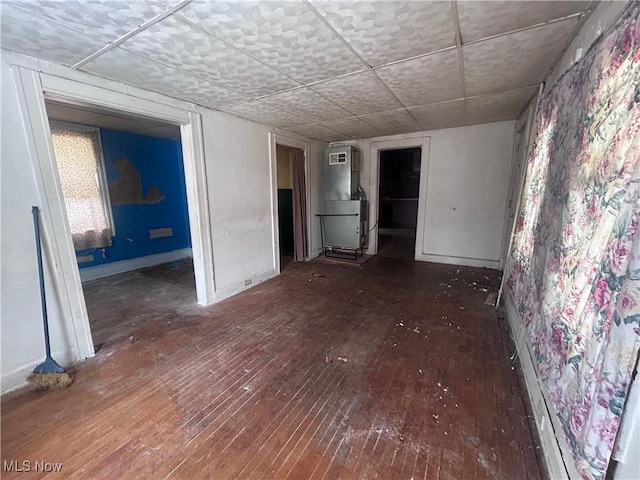 unfurnished room featuring heating unit, wood-type flooring, and baseboards