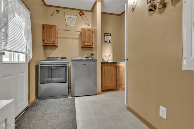 washroom featuring baseboards, washer and dryer, cabinet space, light floors, and crown molding