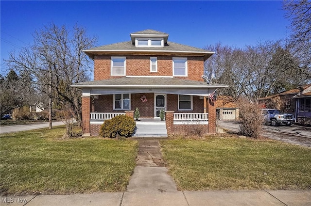 american foursquare style home featuring a porch, brick siding, driveway, and a front lawn