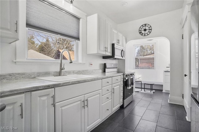 kitchen with stainless steel electric range oven, light countertops, a sink, and white cabinetry