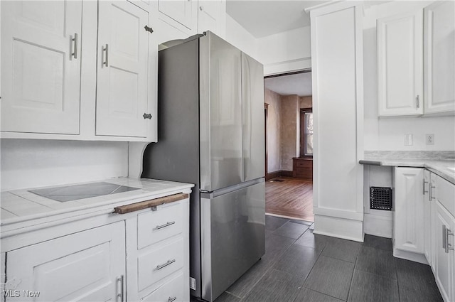 kitchen featuring light countertops, freestanding refrigerator, wood tiled floor, white cabinetry, and baseboards