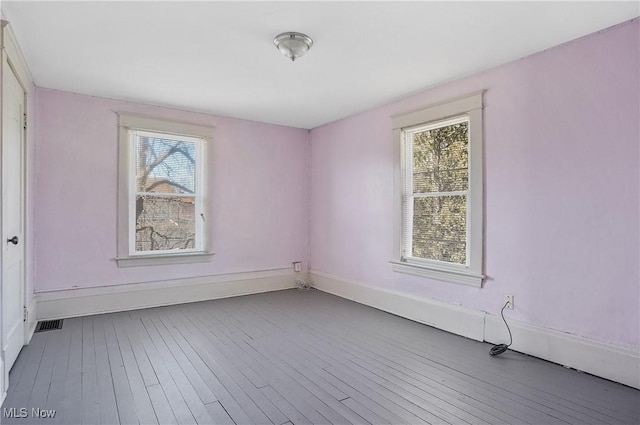 spare room with hardwood / wood-style floors, baseboards, and a wealth of natural light