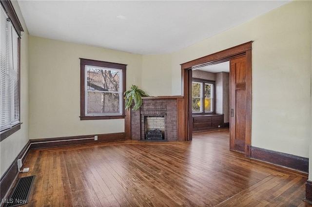 unfurnished living room with hardwood / wood-style flooring, baseboards, a fireplace, and visible vents