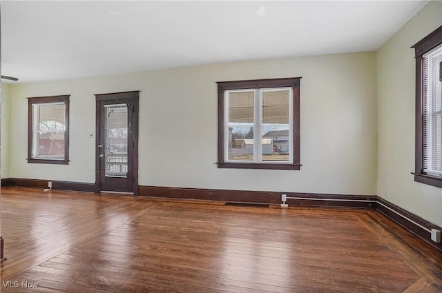 empty room with wood-type flooring, a wealth of natural light, and baseboards