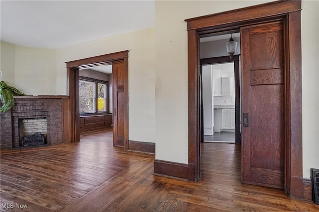 unfurnished living room featuring dark wood finished floors, a fireplace, and baseboards