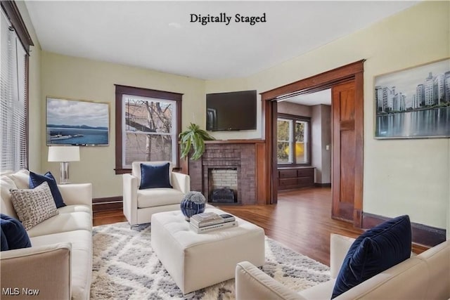 living area featuring a fireplace, wood finished floors, and baseboards