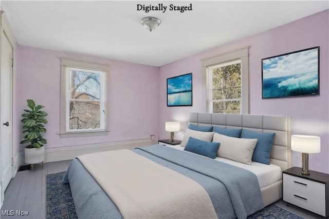 bedroom with multiple windows, wood finished floors, and baseboards