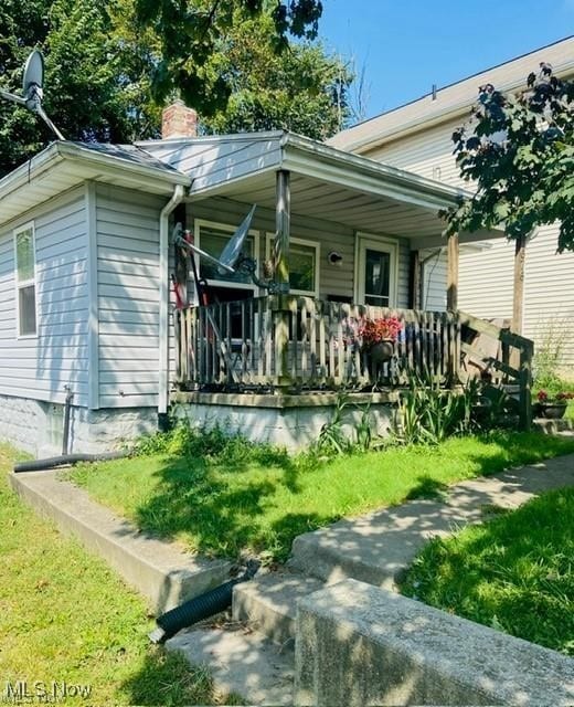 view of front of property with a front yard, covered porch, and a chimney