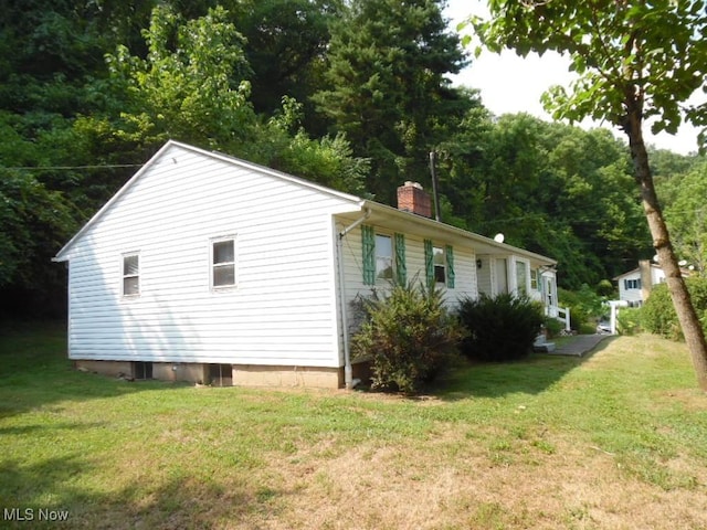 view of side of property featuring a chimney and a lawn