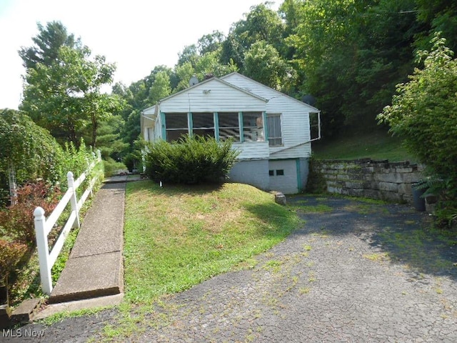 view of front of property featuring driveway, a front yard, and a sunroom