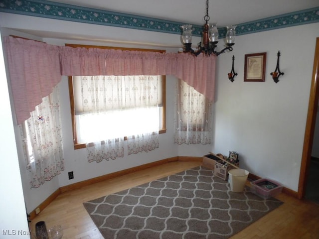 dining room featuring a notable chandelier, baseboards, and wood finished floors